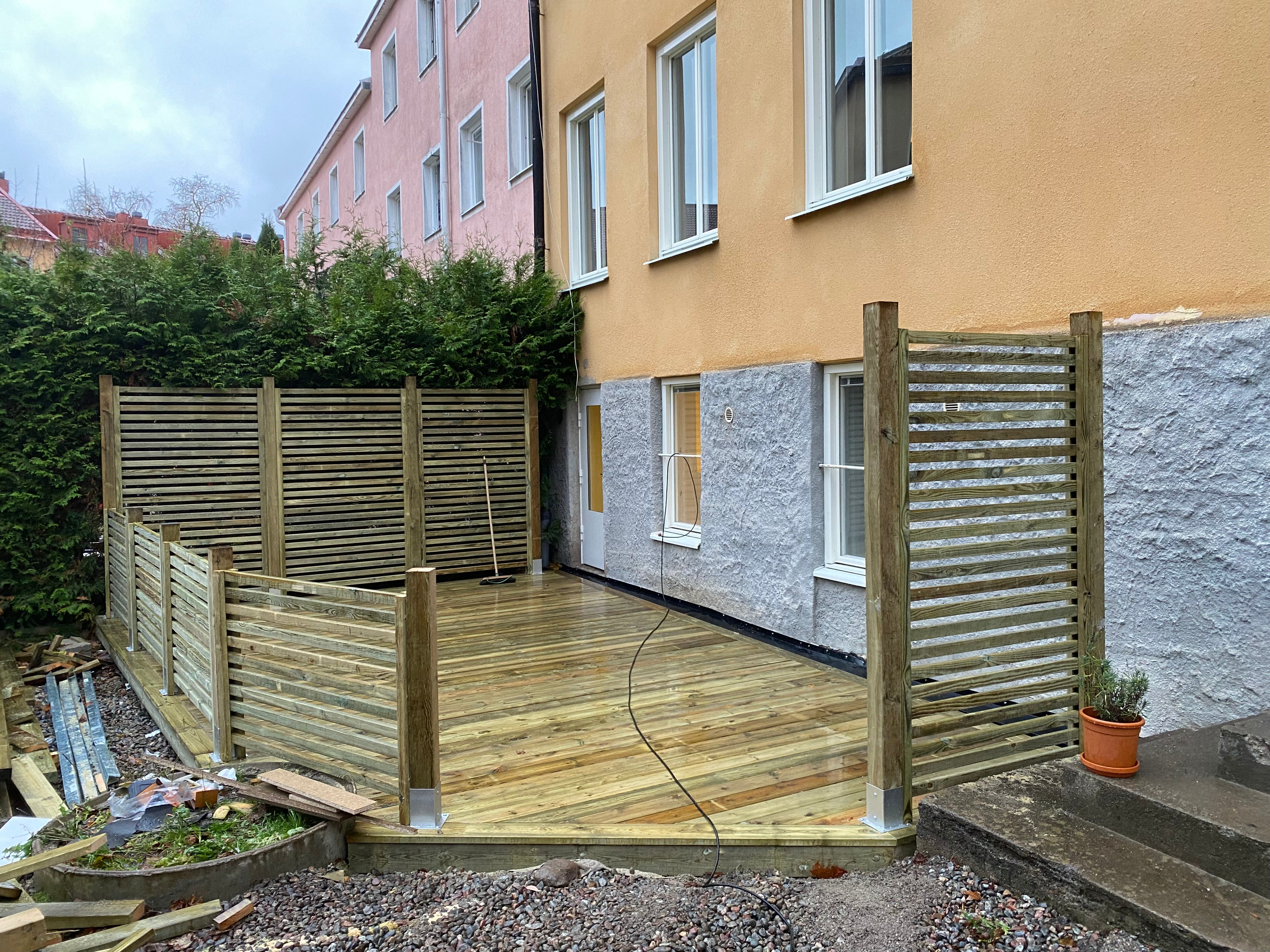 Utealtanbygge med trätrall och skärmar